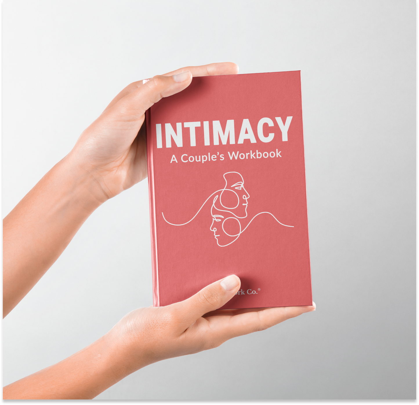 Book titled 'Intimacy: A Couple's Workbook' held by a hand on a light gray background