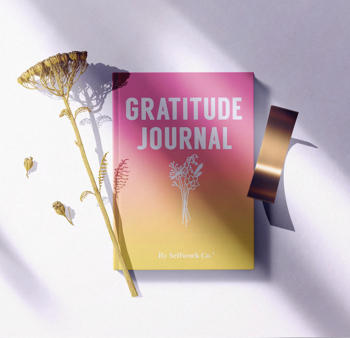 Flat lay of the SelfWork Co. Gratitude Journal with dried flowers, ribbon, and soft natural light shadows