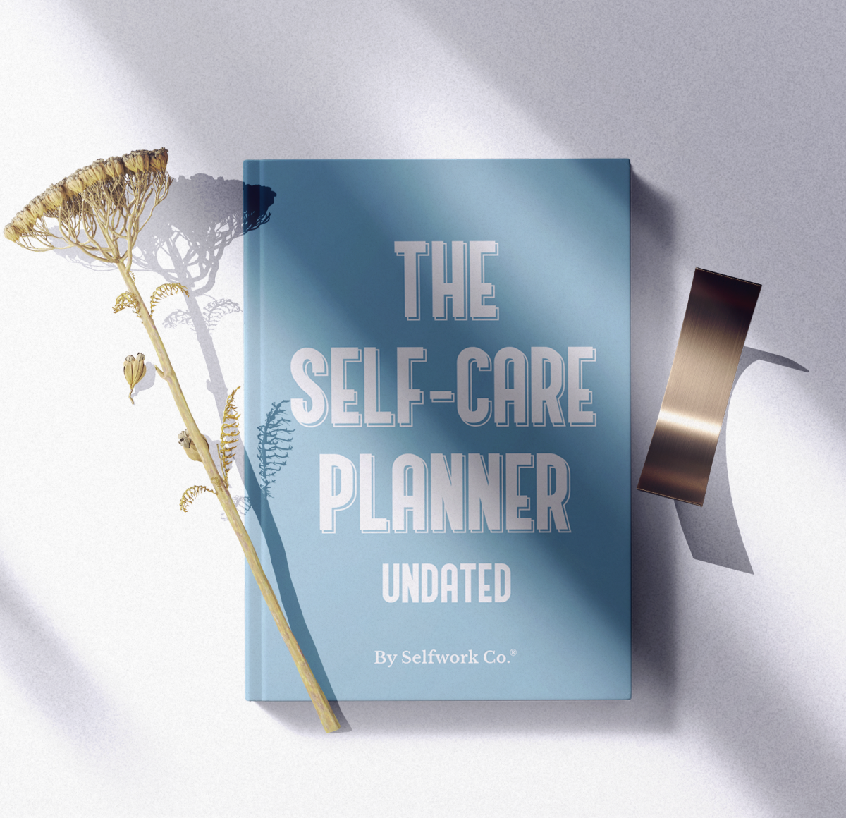 The Self-Care Planner hardcover edition in a flatlay setting with soft lighting and props